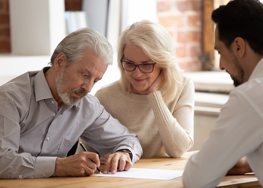 An elderly couple signing documents